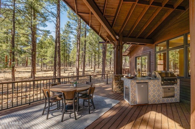 deck with an outdoor kitchen, outdoor dining space, area for grilling, and a sink