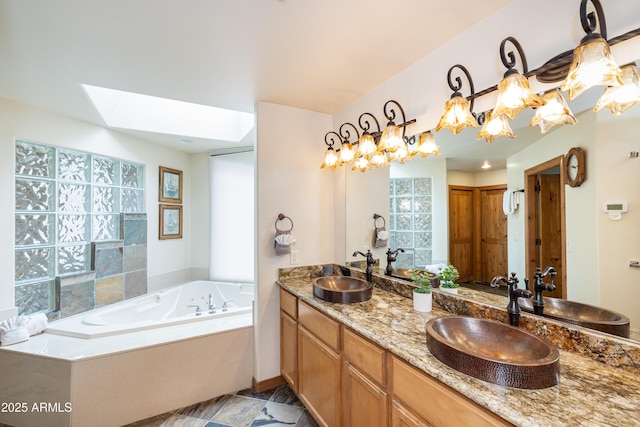 full bath with a garden tub, double vanity, a skylight, and a sink