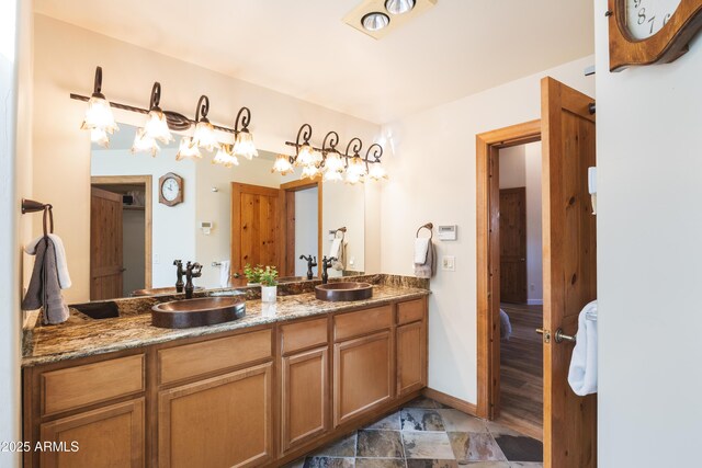 bathroom featuring double vanity, baseboards, and a sink