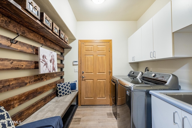 washroom with cabinet space, washing machine and dryer, and light wood-style floors