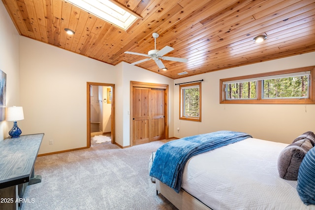 bedroom with vaulted ceiling with skylight, wooden ceiling, carpet flooring, baseboards, and a closet