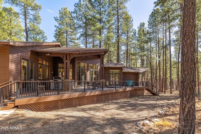 rear view of property featuring a deck and roof with shingles