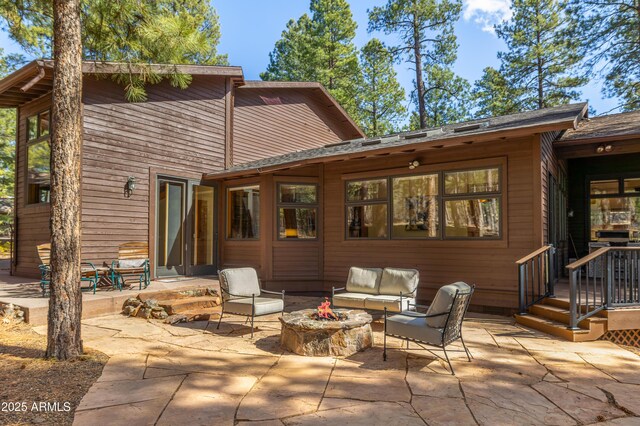 rear view of property featuring a patio area and an outdoor living space with a fire pit