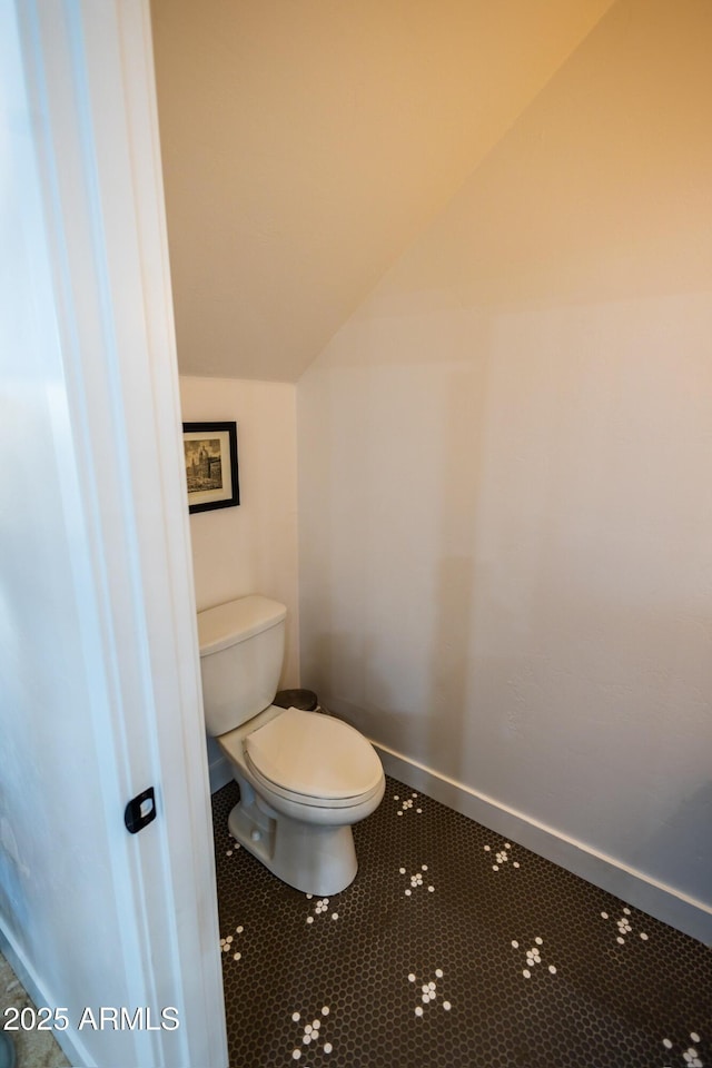 bathroom with tile patterned floors, lofted ceiling, and toilet