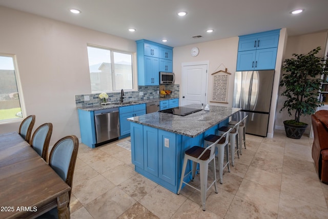 kitchen with sink, blue cabinetry, appliances with stainless steel finishes, a kitchen breakfast bar, and a center island