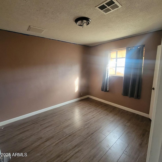 empty room featuring dark hardwood / wood-style floors and a textured ceiling