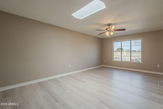 empty room featuring a skylight and light hardwood / wood-style flooring