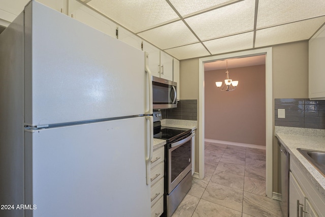 kitchen with decorative backsplash, pendant lighting, white cabinets, and stainless steel appliances