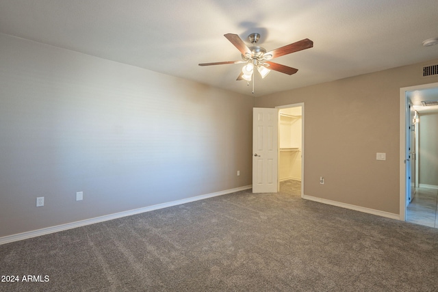 unfurnished bedroom featuring carpet floors, a closet, a spacious closet, and ceiling fan