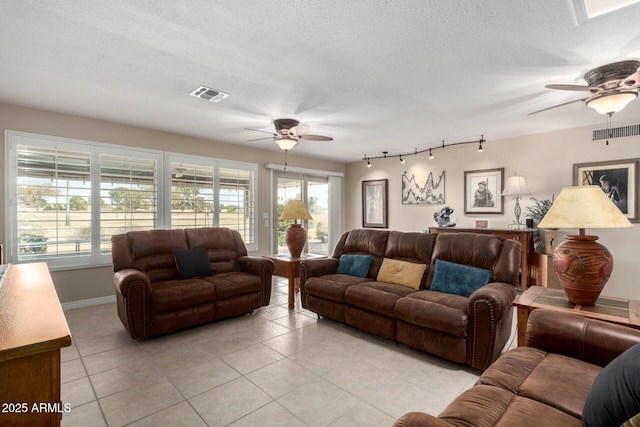 tiled living room with ceiling fan and a textured ceiling