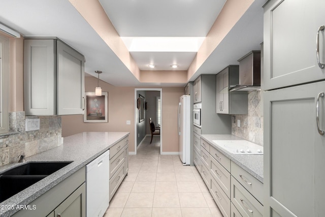 kitchen featuring light stone counters, white appliances, hanging light fixtures, and tasteful backsplash