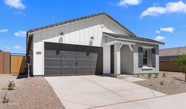 view of front facade featuring board and batten siding, a tiled roof, a garage, and fence