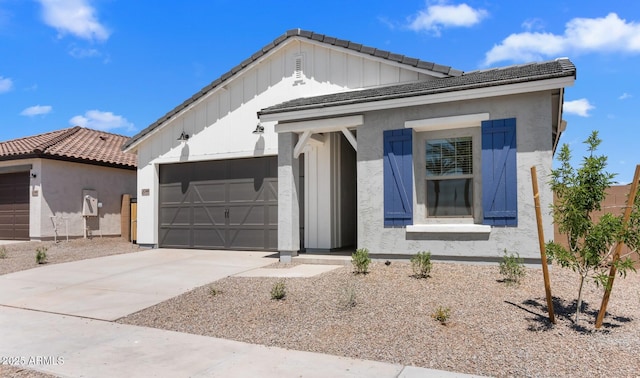 view of front of property featuring an attached garage, a tiled roof, stucco siding, board and batten siding, and driveway