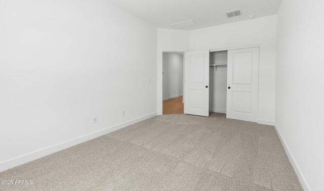unfurnished bedroom featuring baseboards, light carpet, a closet, and visible vents