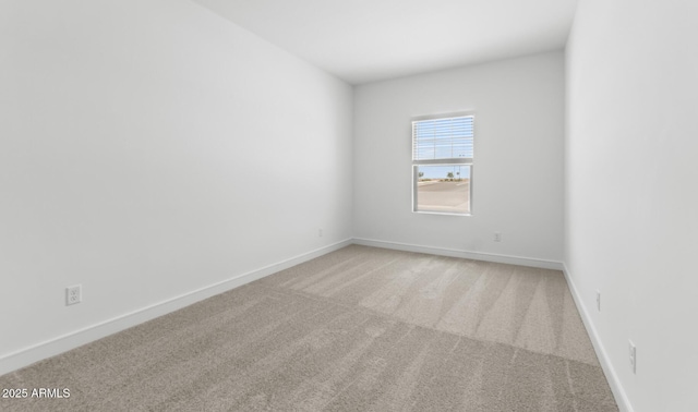 empty room featuring light colored carpet and baseboards