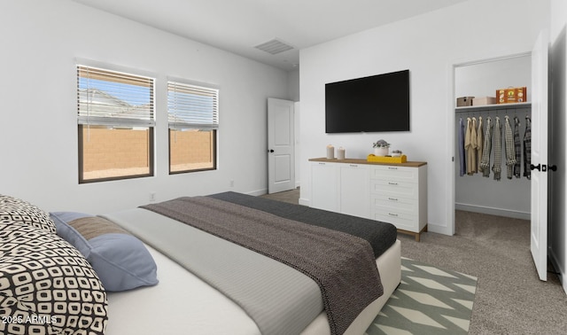 carpeted bedroom with a walk in closet, a closet, baseboards, and visible vents