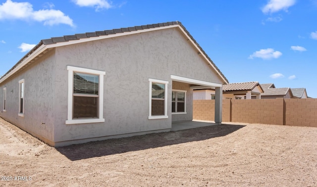 back of property featuring stucco siding, fence, and a patio