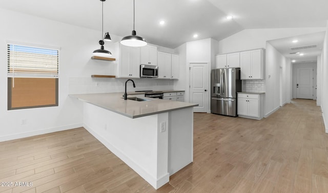 kitchen with a peninsula, a sink, visible vents, appliances with stainless steel finishes, and lofted ceiling