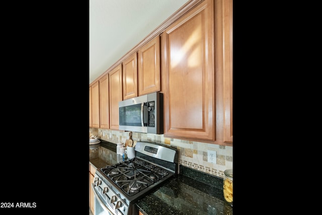 kitchen featuring stainless steel appliances, decorative backsplash, and dark stone counters