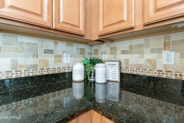 room details featuring dark stone countertops and backsplash