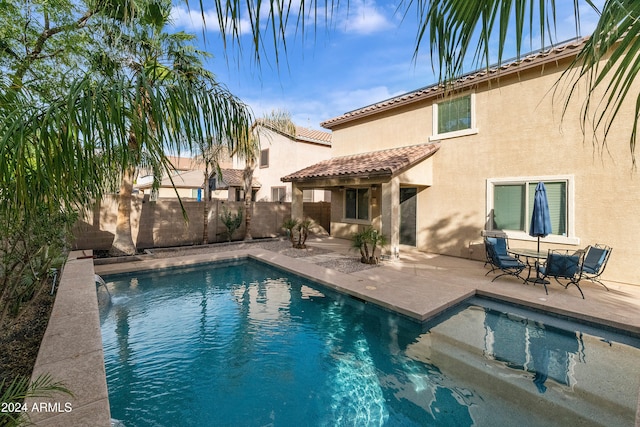 rear view of property featuring a patio area and a fenced in pool