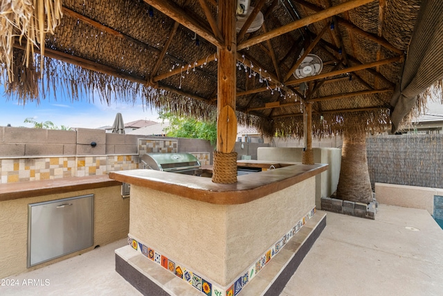 view of patio / terrace featuring a gazebo, a bar, a grill, and an outdoor kitchen