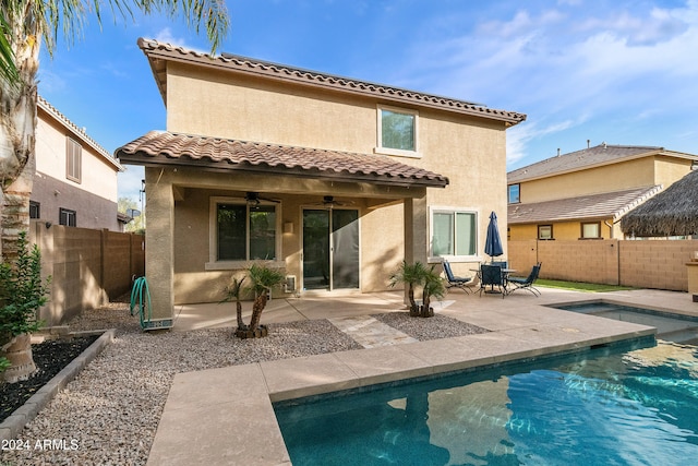 back of property with a patio area, a fenced in pool, and ceiling fan