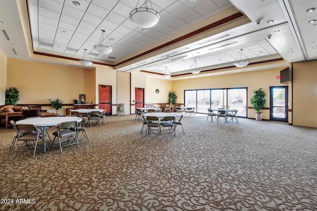 carpeted dining room featuring crown molding, a raised ceiling, and a towering ceiling