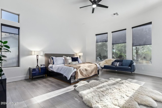 bedroom with hardwood / wood-style floors, ceiling fan, and multiple windows