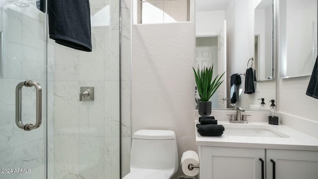 bathroom featuring vanity, toilet, and a shower with shower door