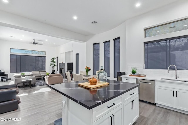 kitchen with dishwasher, a center island, white cabinets, sink, and light hardwood / wood-style floors