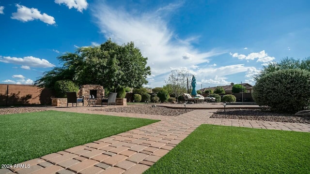 view of yard with an outdoor stone fireplace and a patio area