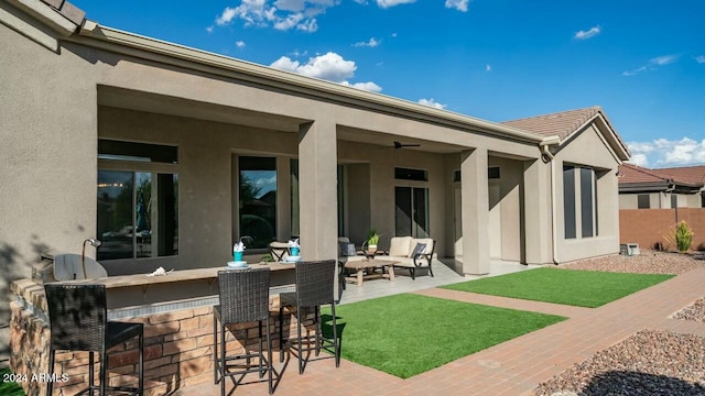 back of property featuring ceiling fan, an outdoor bar, and a patio