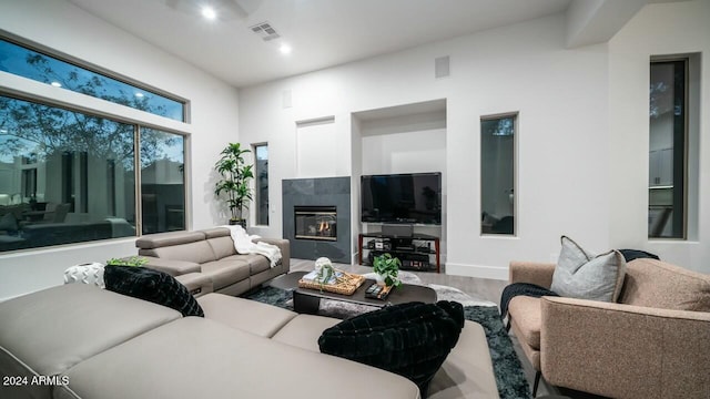 living room with a high ceiling, hardwood / wood-style flooring, and a tiled fireplace