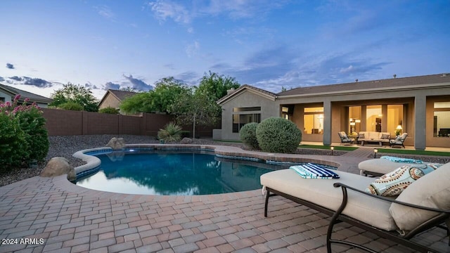 pool at dusk featuring a patio and an outdoor hangout area