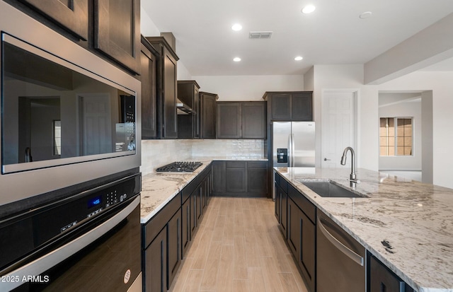 22523 E Orchard Ln, Queen Creek, AZ 85142 - kitchen with stainless steel appliances, a sink, light stone countertops, dark brown cabinetry, and recessed lighting