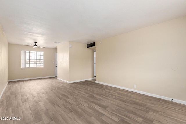 empty room featuring visible vents, baseboards, a ceiling fan, and wood finished floors