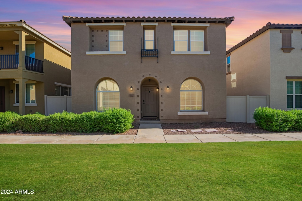 mediterranean / spanish home with a lawn, fence, and stucco siding