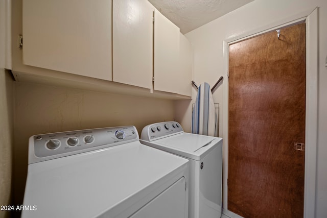 laundry room featuring a textured ceiling, washing machine and clothes dryer, and cabinets