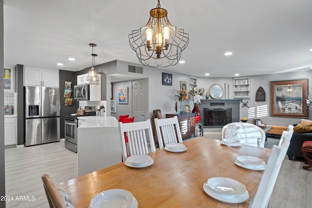 dining space featuring light wood-type flooring and a chandelier