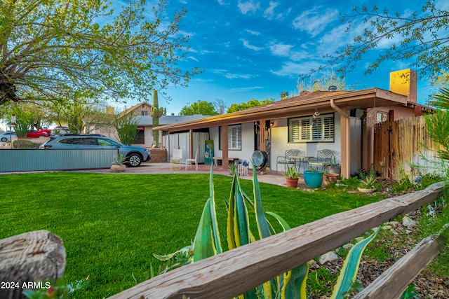 back of house with a lawn and a patio