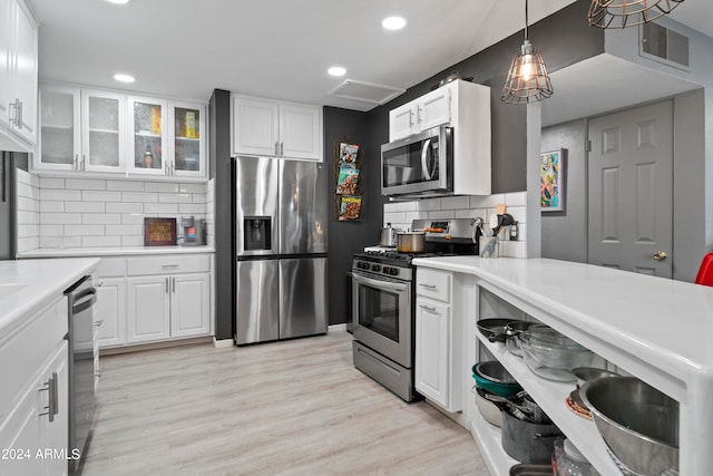 kitchen with light hardwood / wood-style floors, white cabinetry, stainless steel appliances, backsplash, and decorative light fixtures