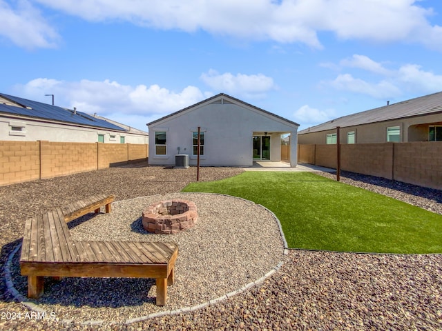 rear view of house featuring central air condition unit, a fenced backyard, a lawn, and stucco siding