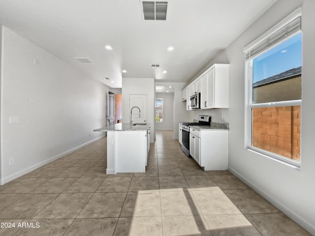 kitchen featuring visible vents, appliances with stainless steel finishes, light stone counters, white cabinetry, and a sink