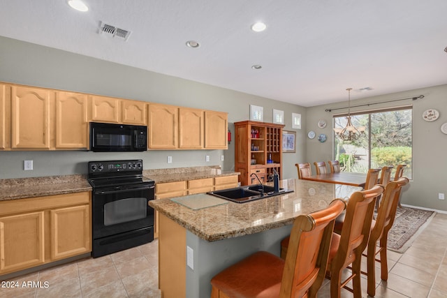 kitchen with hanging light fixtures, a kitchen bar, light tile floors, sink, and black appliances