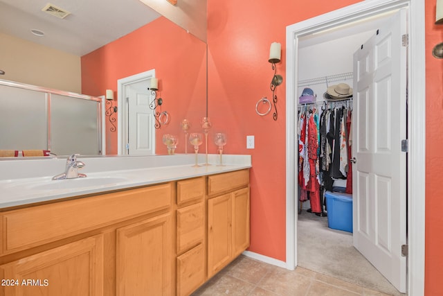 bathroom with oversized vanity, an enclosed shower, and tile flooring