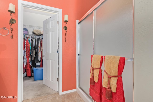 bathroom featuring a shower with door and tile flooring