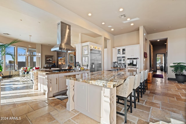 kitchen featuring island exhaust hood, stainless steel appliances, sink, hanging light fixtures, and a large island