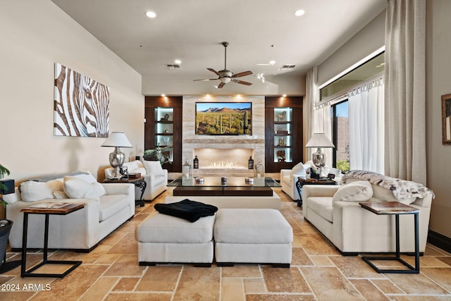 living room featuring a large fireplace and ceiling fan