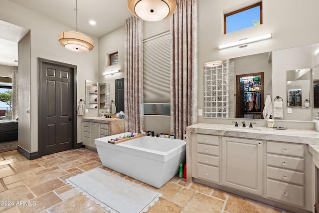 bathroom featuring vanity, a towering ceiling, and a bath